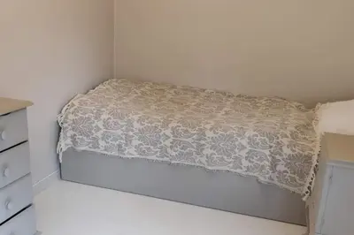 a bed in a white room with a blanket on it at Hus med utsikt på leira . 4 sengeplasser. in Leira