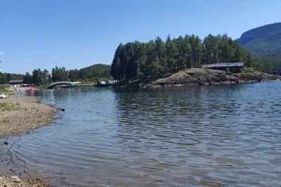 a large body of water with trees in the background at Hus med utsikt på leira . 4 sengeplasser. in Leira