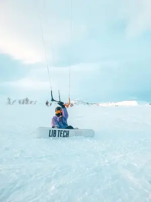 a person on a snowboard under a parachute in the snow at Peaceful Oasis. Panoramic forest- & mountain view. Sauna. in Beitostøl