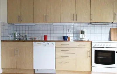a kitchen with wooden cabinets and a white dishwasher at Amazing Home In Dale I Sunnfjord in Gjølanger
