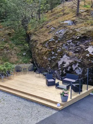 a wooden deck with chairs and a table and chairs at Kvamsdal Pensjonat 1 in Eidfjord