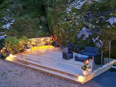 a wooden deck with furniture and lights on it at Kvamsdal Pensjonat 1 in Eidfjord