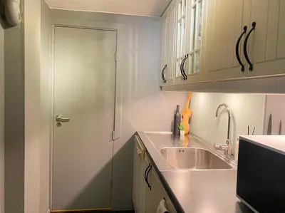 a kitchen with a sink and a glass door at Cosy and well-equipped apartment with free parking in Trondheim
