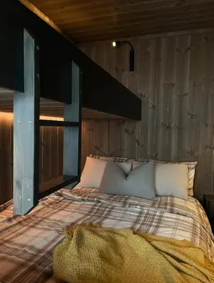 a bedroom with a bed with a wooden wall at Sogndal Chalet in Sogndal