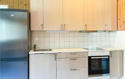 a kitchen with white cabinets and a stainless steel refrigerator at 2 Bedroom Stunning Home In Dovre in Dovre
