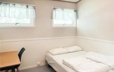 a room with a bed and a table and two windows at 2 Bedroom Stunning Home In Dovre in Dovre