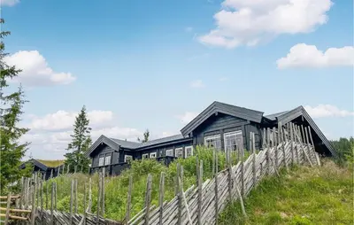 a house on top of a hill with a fence at Beautiful Home In Sjusjøen With Sauna in Sjusjøen