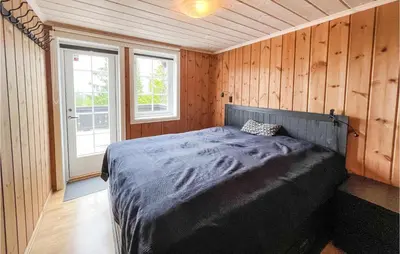 a bedroom with a bed in a room with wooden walls at Beautiful Home In Sjusjøen With Sauna in Sjusjøen