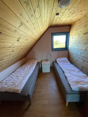 two beds in a room with wooden ceilings and a window at Nautnes Seaside Apartments A5 in Nautnes
