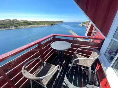 a balcony with a table and chairs on a boat at Nautnes Seaside Apartments A5 in Nautnes