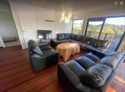 a living room with a black leather couch and a table at Nautnes Seaside Villa in Nautnes