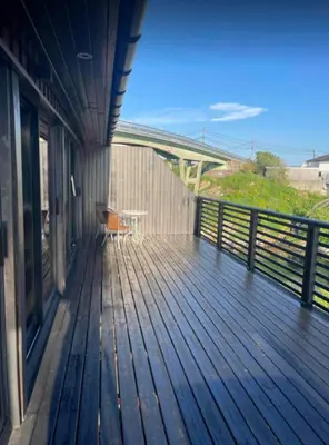 a wooden deck with a table on the side of a building at Nautnes Seaside Villa in Nautnes