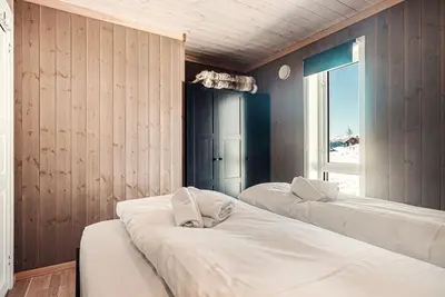 two beds in a room with wooden walls and a window at Harevadet 211 in Hornindal