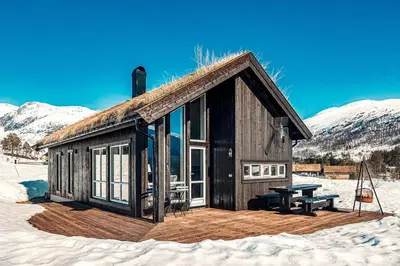 a wooden cabin with a picnic table in the snow at Harevadet 211 in Hornindal