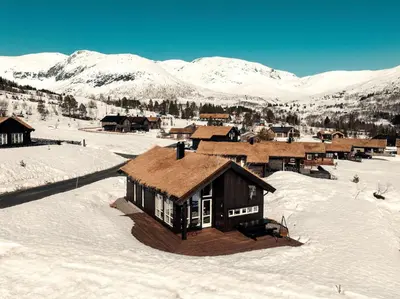 a cabin in the snow with mountains in the background at Harevadet 211 in Hornindal
