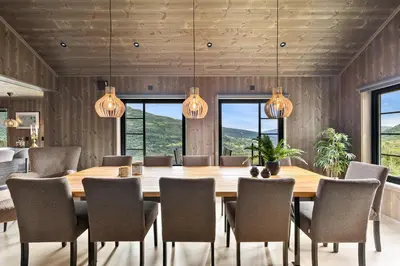 a dining room with a large wooden table and chairs at Hodlekvevegen 307 in Sogndal