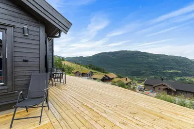 a wooden deck with a chair on top of a house at Hodlekvevegen 307 in Sogndal