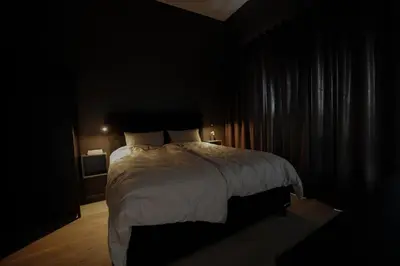 a dark bedroom with a bed with white sheets and pillows at Elegant apartment in Trysil Alpine Lodge in Trysil