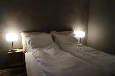 a large white bed with two lamps on both sides at Koselig leilighet i Langevåg in Holen