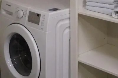 a white washing machine in a bathroom with towels at Koselig leilighet i Langevåg in Holen