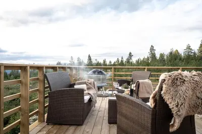 a patio with chairs and a grill on a deck at Arctic Dome Gudbrandsdalen in Sør-Fron
