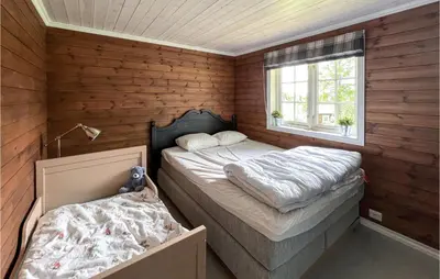 two beds in a room with wooden walls and a window at 4 Bedroom Beautiful Home In Nord-Torpa in Nord Torpa