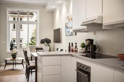 a kitchen with white cabinets and a dining room at Corner Apartments in Bergen