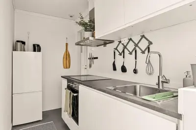 a white kitchen with a sink and a refrigerator at Dinbnb Apartments I Views & Street Parking in Sandviken in Bergen