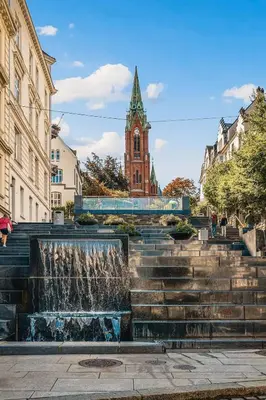 a fountain in front of a building with a clock tower at Dinbnb Apartments I Characteristic Townhouse with Bathtub in Bergen