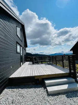 a wooden deck next to a building with chairs on it at Hodlekvevegen 308 - Flott hytte midt i skisenteret in Sogndal