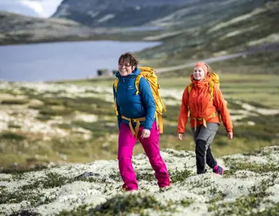 two people walking on a hill with a backpack at Smuksjøseter Fjellstue in Høvringen