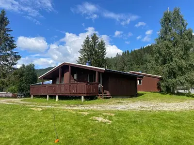 a cabin with a grass field in front of it at Midttun Camping og Feriehytter in Vossestrand