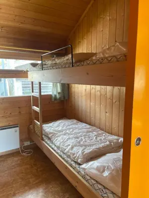 a bunk bed in a wooden cabin with a bed in it at Midttun Camping og Feriehytter in Vossestrand