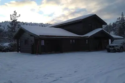 a snow covered cabin with a car parked in front of it at Stor og koselig hytte i Stryn in Stryn