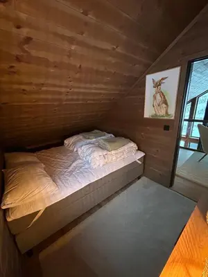 a small bed in a room with wooden walls at Rindabotn Fjelltun ski in-ski out in Sogndal