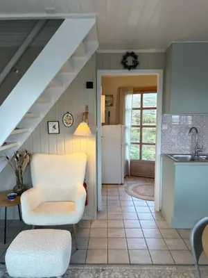 a kitchen with a staircase and a chair and a sink at Sveggvika Atlantic Home in Averoy