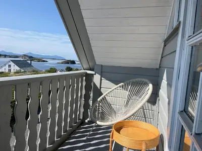 a white chair on a balcony with a view of the ocean at Sveggvika Atlantic Home in Averoy