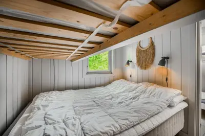 a bed in a room with a wooden ceiling at Lillehammer Turistsenter Camping in Lillehammer