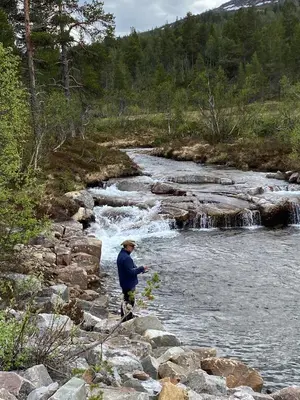 a man is standing on rocks in a river at Hovden Høyfjellsenter in Hovden
