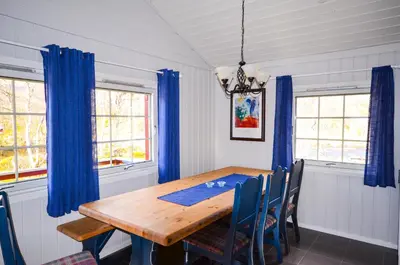 a dining room with a wooden table and blue curtains at Hovden Høyfjellsenter in Hovden