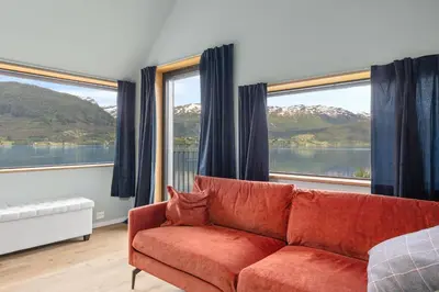a living room with a red couch and large windows at Modern house by the Fjord in Sandane, Nordfjord. in Sandane