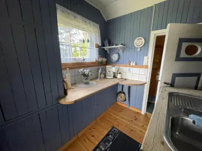 a kitchen with blue walls and a counter and a window at Sjarmerende hytte omgitt av vakker natur in Molde