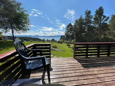 a bench on a wooden deck with a view of the ocean at Sjarmerende hytte omgitt av vakker natur in Molde