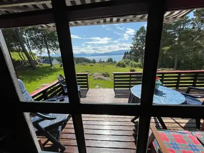a view from a window of a deck with a table and chairs at Sjarmerende hytte omgitt av vakker natur in Molde