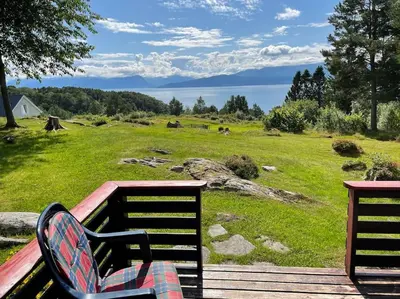 a bench sitting on a deck with a view of a field at Sjarmerende hytte omgitt av vakker natur in Molde