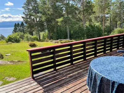 a wooden deck with a table and a fence at Sjarmerende hytte omgitt av vakker natur in Molde