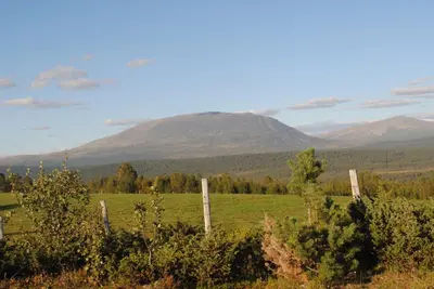 a fence in a field with mountains in the background at Lusæter Timber Cabins in Heidal