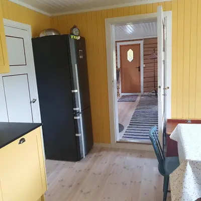 a kitchen with a black refrigerator and a hallway at Brekkveien 81-meget sentral hytte,15 min å gå til Røros sentrum in Røros