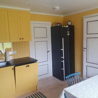a kitchen with yellow cabinets and a black refrigerator at Brekkveien 81-meget sentral hytte,15 min å gå til Røros sentrum in Røros
