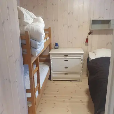 a bedroom with two bunk beds and a night stand at Brekkveien 81-meget sentral hytte,15 min å gå til Røros sentrum in Røros